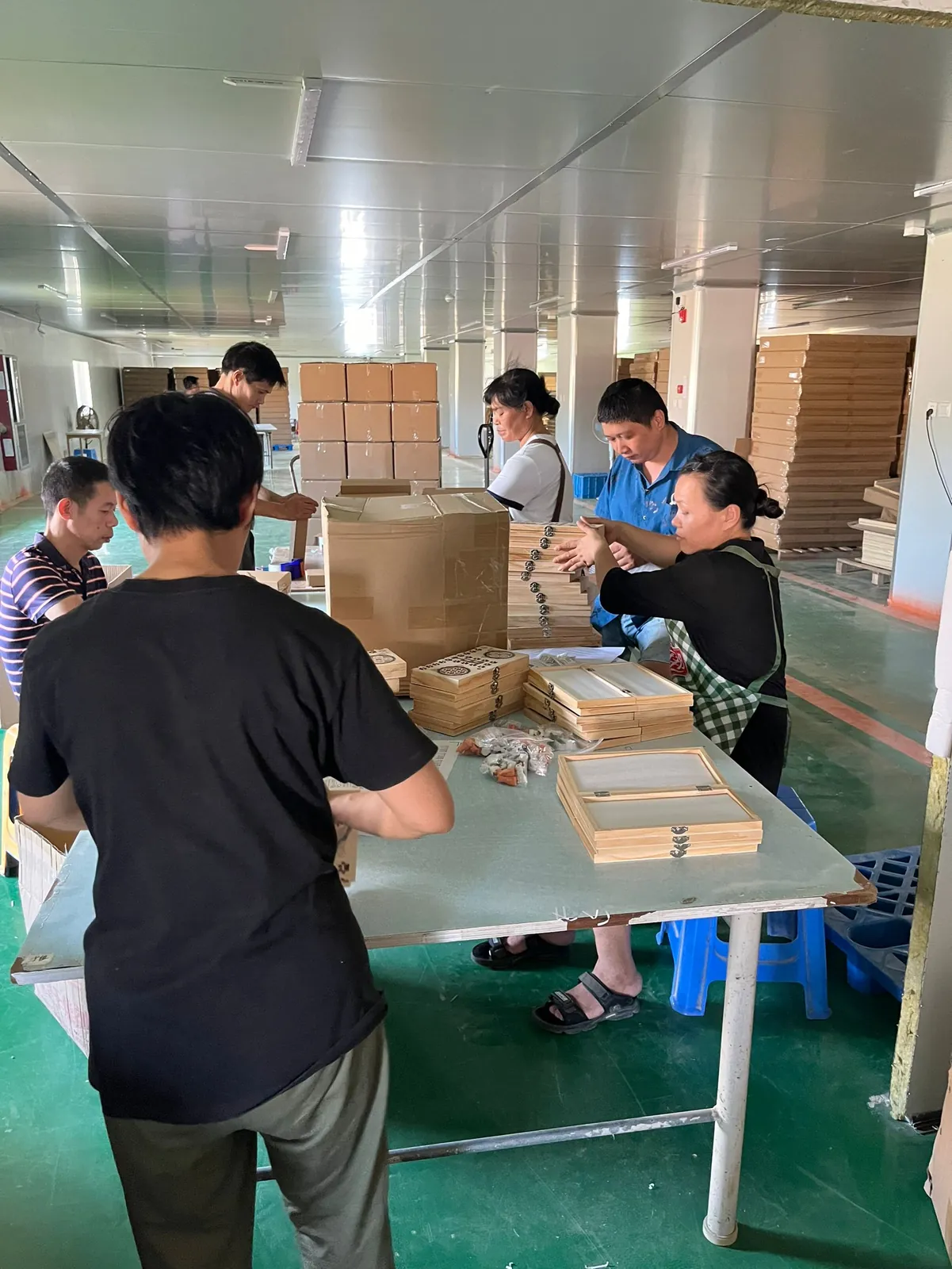 Assembly table where several workers assemble wooden drawers and boxes